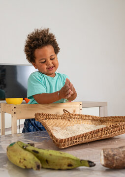 Curious african child playing with rice in a tipical congolese basket