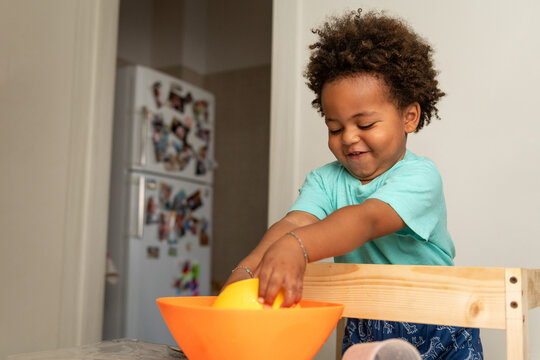 Focused toddler boy playing with bowls and water at home