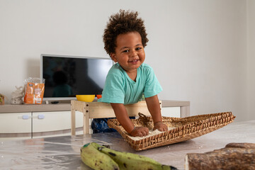 Happy african child playing with rice in a tipical congolese basket