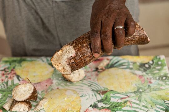 Male hands peeling the cassava root in the kitchen