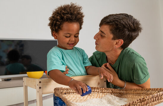 Mother and son playing together with winnowing tray and rice