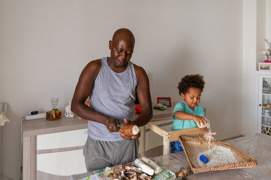 Father and son preparing together cassava roots and rice 