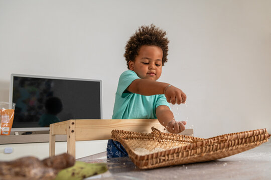 Curious african child playing with rice in a tipical congolese basket