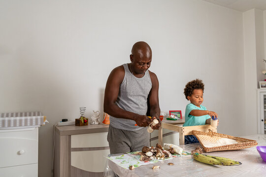 Father and son preparing together cassava roots and rice 