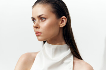 Elegant portrait of a young woman with long hair, wearing a white sleeveless top, in a soft light...