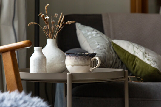 Side table with nature themed decor and a cup of tea or coffee.