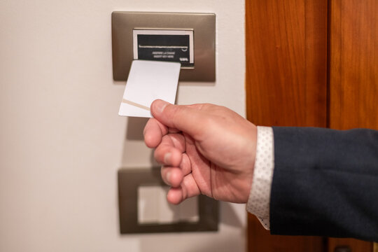 Businessman's hand uses keycard in hotel room to turn on the light