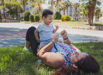 Joyful mother and child playing outdoors in a sunny park surrounded by palm trees