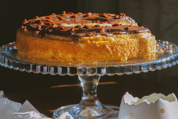 Traditional Polish bundt-style cake with rich chocolate glaze and goji berries, served on elegant glass stand, festive homemade dessert for Easter or special occasions