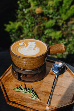 Latte with swan art in ceramic cup on wooden tray