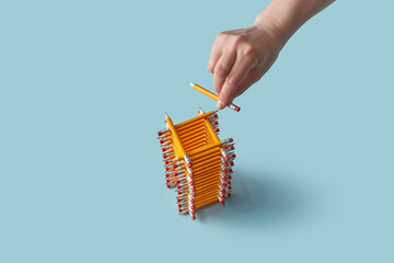 Hand building pencil tower on blue background