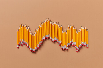 Pencils shaped like data wave on light brown background