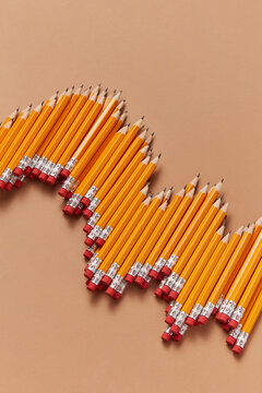 Pencils arranged like graph lines on light brown background