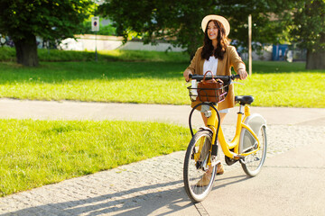 Young woman walking with electric bicycle on park path, enjoying sunny day. Sustainability or eco...