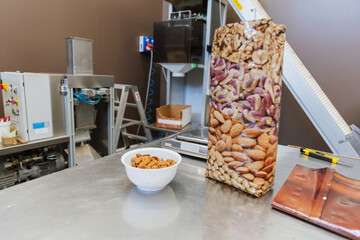 A bowl of almonds next to a plastic bag during the process of packaging