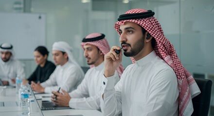 Focused businessman in traditional attire participates in a serious business meeting, actively listening and engaging in a phone call.