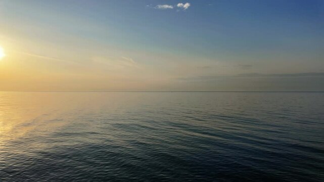 Serene view of sun setting over vast sea horizon with clear and soft light. Time Lapse.