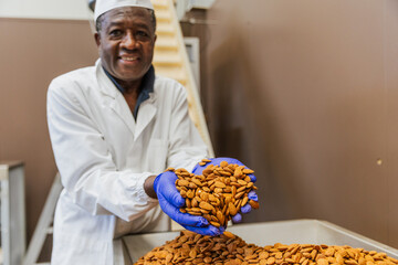 Warehouse worker smiling and holding almonds in hands