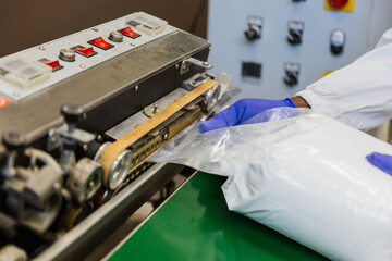 Close up of worker’s hands sealing a glucose bag with heat sealer in warehouse