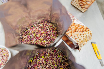 Close up of pistachios in plastic bags on a table with a cutter during packaging process