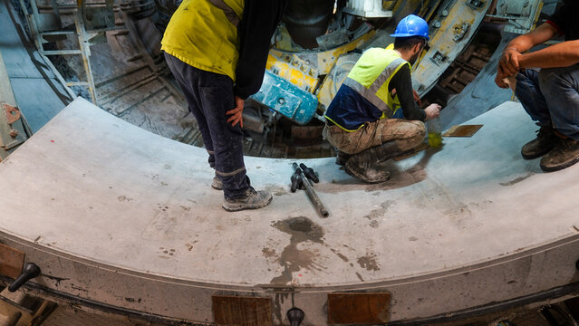 Workers Operating Tunnel Boring Machine Interior at Construction Site