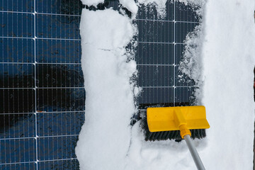 Cleaning solar panels from snow.Yellow brush clears snow from solar panel close-up. Getting...