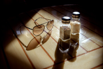 Glasses, pepper shaker and salt shaker on the table in backlight