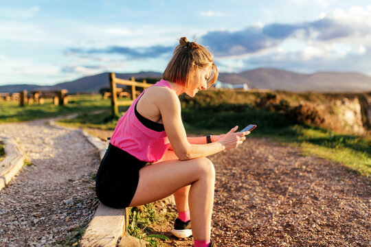 Runner woman checking phone outdoors