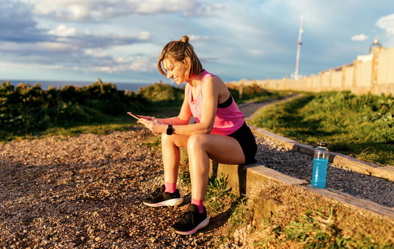 Runner woman sitting and checking phone