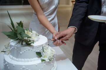 Bride and groom cutting wedding cake together