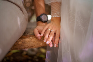 Man and woman, newlyweds holding hands with blurred background.