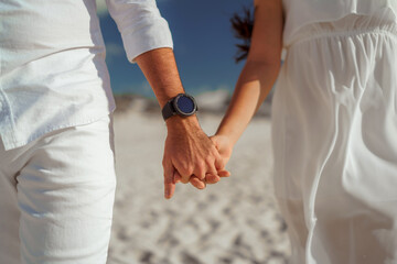 Man and woman, newlyweds holding hands with blurred background.