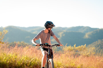 Fototapeta premium Male cyclist wearing a protective helmet while riding a mountain bike on a dirt trail during a sunny day. Promoting outdoor safety and active lifestyle.