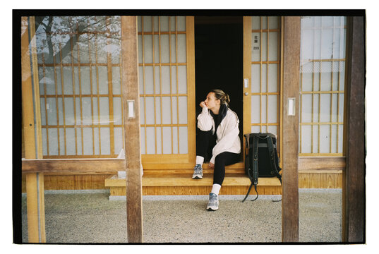 Traveler Sitting at Traditional Japanese Guesthouse Entrance