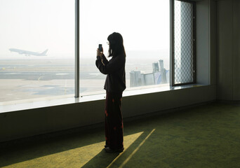 Woman taking photo at airport during sunrise