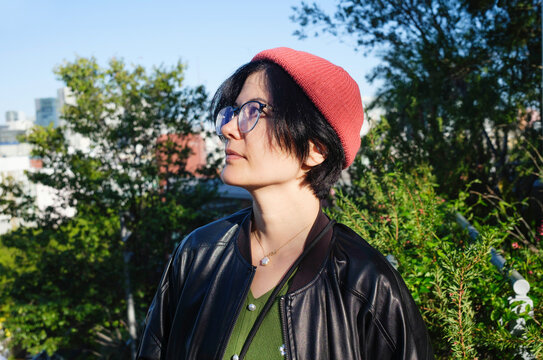 young woman wearing a beanie and jacket looks up towards the skyline