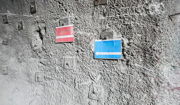 Directional Signs Highlighting Red and Blue Designs on the Wall