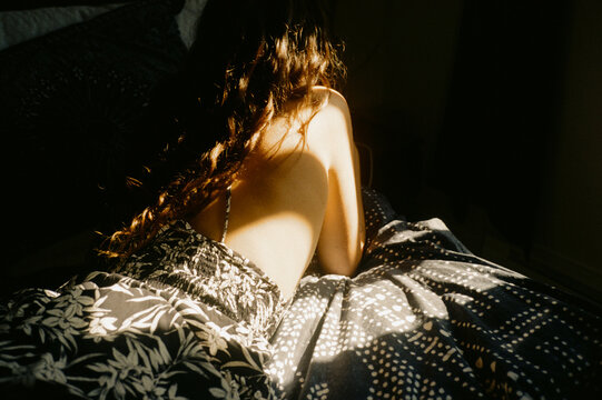 young woman with long curly hair on bed
