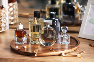 Bottles of different perfumes and accessories on wooden table, closeup