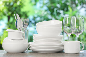 Different clean dishes on wooden table against blurred green background