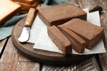 Tasty chocolate butter and knife on wooden table, closeup