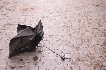 Broken umbrella on wet pavement outdoors. Space for text
