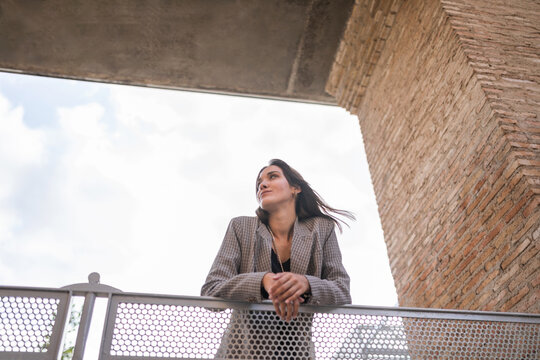 Young woman smiling while leaning on a railing in the city