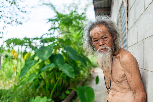 Elderly farm worker standing by a rural shelter in Thailand