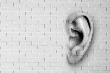 Human ear in white brick wall, space for text. Eavesdropping, concept that even walls have ears