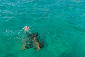 Drowning woman with raised hand. Hand drowning person sticking out of the water.
