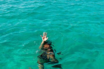Drowning woman with raised hand. Hand drowning person sticking out of the water.
