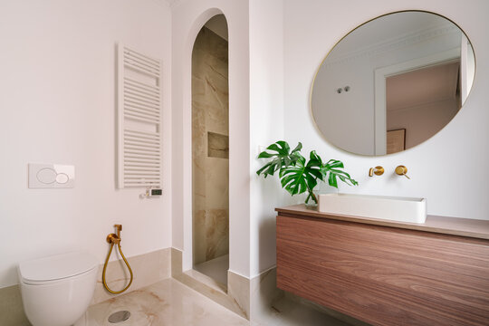 Modern bathroom with arched shower and golden fixtures