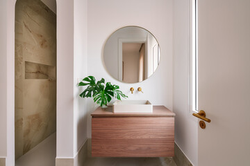 Elegant bathroom with round mirror and wood vanity
