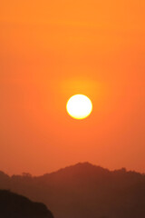 Obraz premium orange sunset photo with the sillhouette of hill